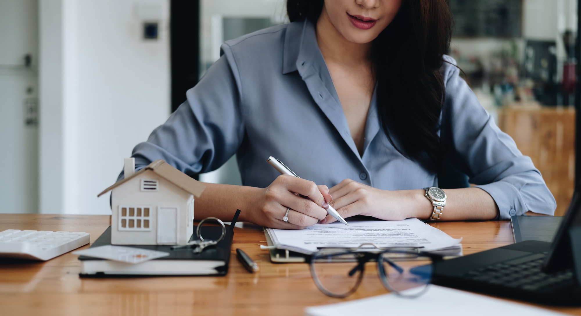 Hands of businesswoman signing leasing home documents and have a apartment keys on paperwork